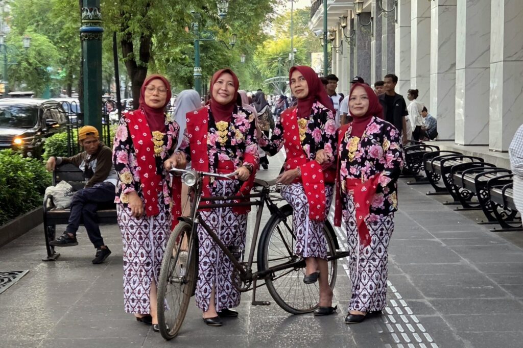 Kobiety w tradycyjnych strojach batikowych z zabytkowym rowerem na Malioboro