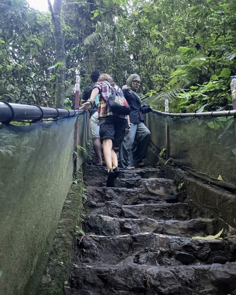 Turyści schodzący po stromych kamiennych schodach na trasie do Tumpak Sewu