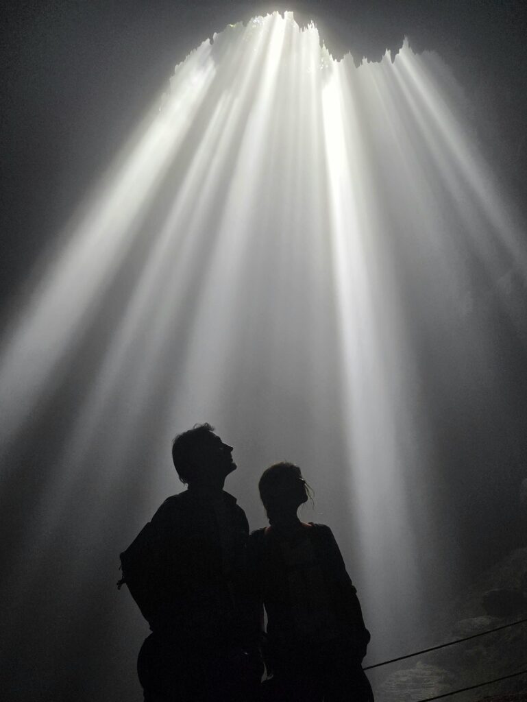 Dwie sylwetki pod snopem światła Heaven’s Light w Luweng Grubug