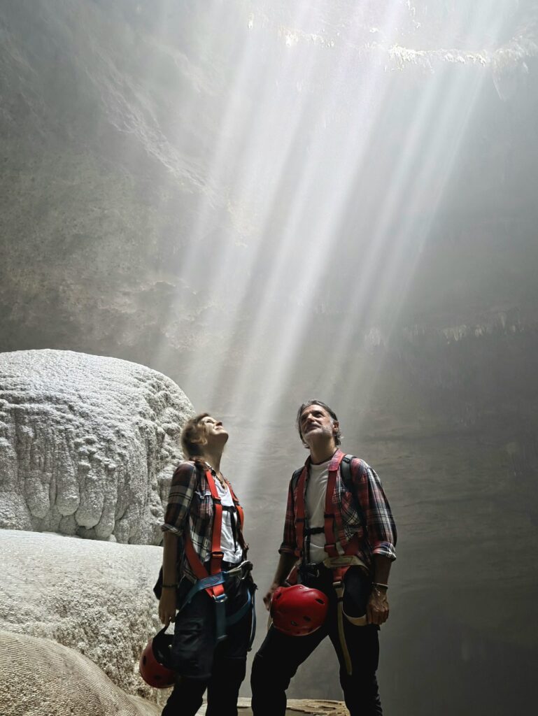 Para turystów w kaskach pod snopem Heaven’s Light w Luweng Grubug