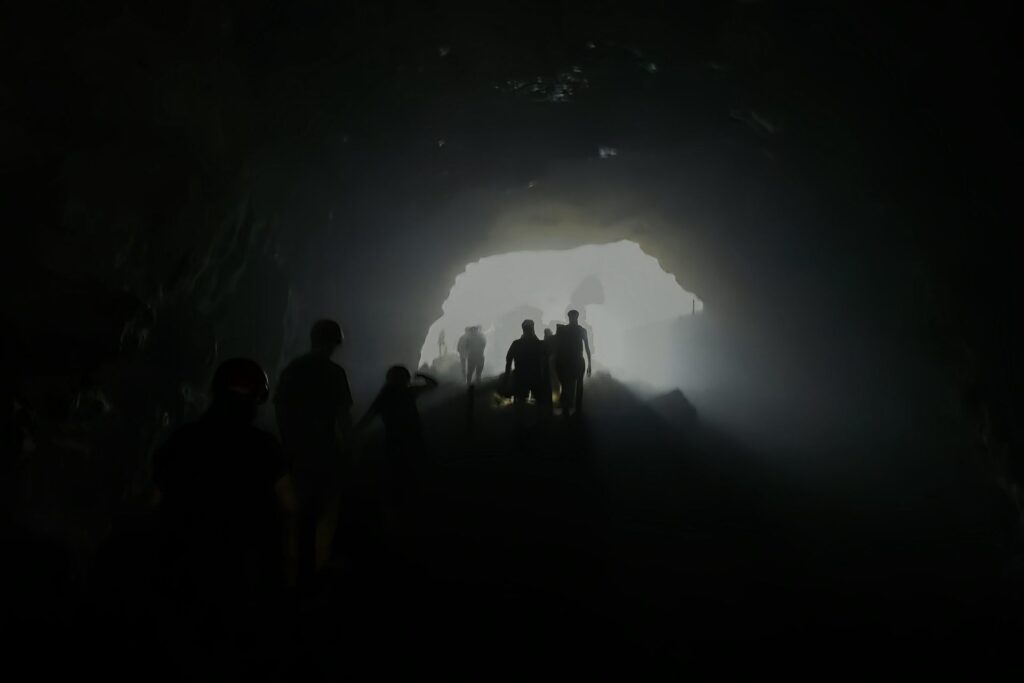 Sylwetki ludzi w ciemnym korytarzu prowadzącym do Luweng Grubug